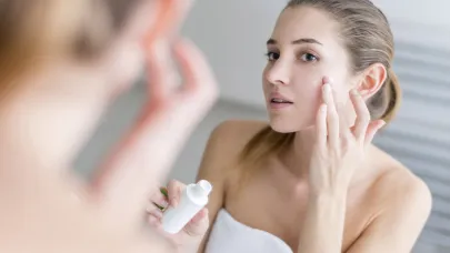 Woman applying cream on her face in a bathroom